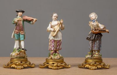 three figurines of men playing musical instruments on a table
