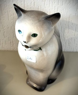 une figurine de chat posée sur une table, avec une étiquette autour du cou