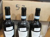 trois bouteilles de vin sont posées sur une table devant une boîte en carton