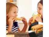two girls that are eating a sandwich in front of a grill