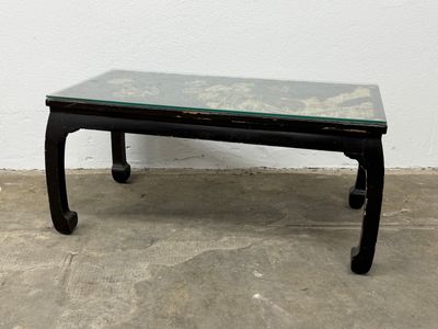 a black table with a glass top sitting on a cement floor