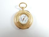 une montre de poche en or avec un cadran blanc sur une surface blanche
