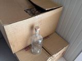 a box with a bottle on top of it next to a box with a cat inside of it