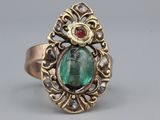Gros plan sur une bague en or ornée d'une pierre verte