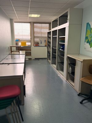 une pièce avec un bureau, des chaises et une carte accrochée au mur