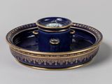 une assiette bleue et dorée sur laquelle figure une horloge