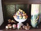 a white vase filled with fruit on top of a wooden shelf