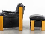 black leather chair and foot stool in a room with a white wall