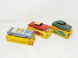 three toy cars are sitting on top of boxes on a white surface