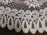 un gros plan sur une dentelle blanche posée sur un morceau de tissu