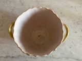 a white bowl with a yellow handle on a marble table