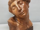 un gros plan sur une sculpture représentant une tête d'homme posée sur un socle en bois
