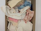 a cardboard box filled with baby clothes and a hat
