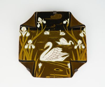 une assiette marron et blanche sur laquelle est représenté un cygne