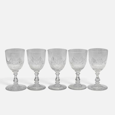 quatre verres à vin transparents empilés les uns sur les autres sur une surface blanche