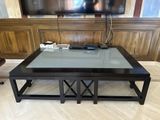 a glass top coffee table with a tv on the wall in the background