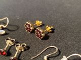 several pairs of earrings are sitting on a black surface