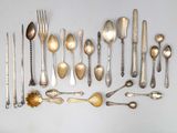 de nombreuses cuillères en argent et des cuillères ordinaires disposées sur une table