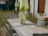 une table en bois avec des chaises et des parasols dans le jardin