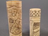 pair of carved ivory vases with figures on them on a gray surface