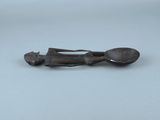une vieille figurine en bronze représentant un homme tenant une cuillère et un repose-cuillère