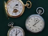 three different types of pocket watches on a green surface