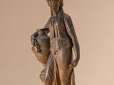 statue of a woman holding a vase and a vase on a beige background