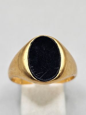 a close up of a gold ring with a black stone