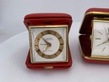 two clocks that are sitting on a white table