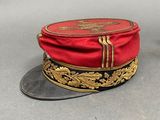 pair of red and black hats with gold trims on a gray surface