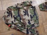 a camouflage jacket laying on the floor next to a pair of shoes