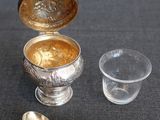 a silver cup with a spoon next to it on a table