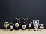 de nombreux vases de formes variées posés sur une table, sur fond noir