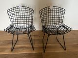 pair of black wire chairs sitting on top of a wooden floor