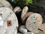 a pile of old wooden spools sitting on the side of the road