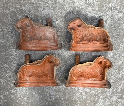 three sheep and sheep figurines sitting on top of a cement surface