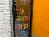 a refrigerator that has drinks in it next to a wall