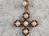 a gold cross necklace with pearls on a chain