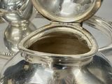 a silver pot sitting on a silver tray with a mirror in the background