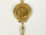 a close up of a gold coin with a tassel on a white surface