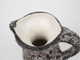a black and white vase with a handle on a table