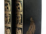 un vieux livre à la couverture noire ornée d'illustrations dorées