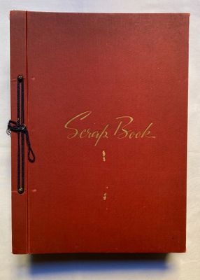 un livre rouge avec une écriture dorée posé sur une surface blanche