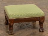 un petit repose-pieds sur lequel est posé un coussin vert