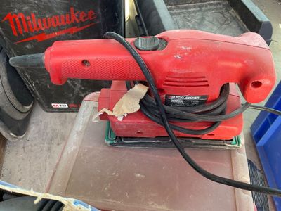 une ponceuse électrique rouge posée sur une table