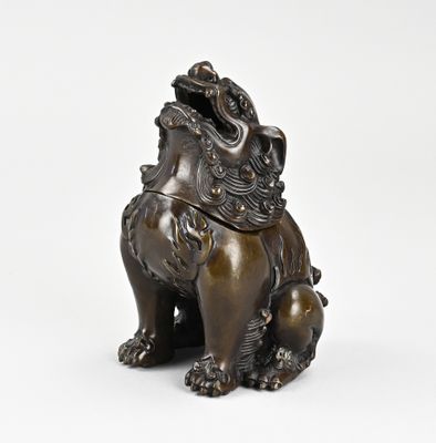 une statue en bronze représentant un lion assis sur ses pattes arrière