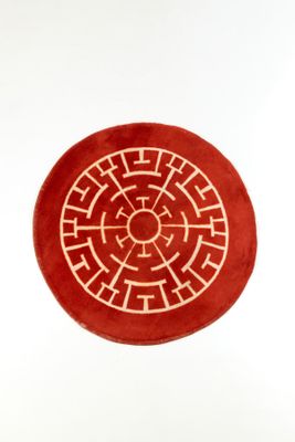 un tapis rond rouge orné d'un motif blanc
