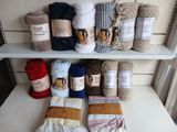 de nombreux types de couvertures et de plaids posés sur une étagère