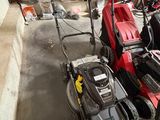 Plusieurs tondeuses à gazon sont alignées en rang dans un garage