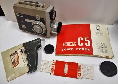 un appareil photo et un livre posés sur une table, à côté d'autres objets